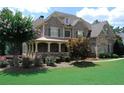 Charming home exterior features a stone facade, covered porch, mature trees, and beautifully landscaped front yard at 5120 Parkwood Oaks Ln, Smyrna, GA 30126