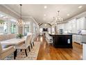 Bright kitchen featuring a large island with barstool seating, white cabinets, hardwood floors, and elegant chandeliers at 5120 Parkwood Oaks Ln, Smyrna, GA 30126