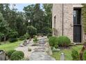 Stone path leading to a brick home with a cozy seating area and lush greenery at 7455 Old Rico Rd, Chattahoochee Hills, GA 30268