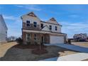 Two-story home with brick and white siding, charming covered porch with detailed wood supports, and a two-car garage at 3941 Adler Cir, Buford, GA 30519