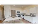 Kitchen and dining area with stainless steel appliances, white cabinets, and a marble-topped table at 312 Naples Dr, Locust Grove, GA 30248