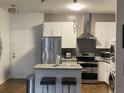Well-lit kitchen features an island with barstools, stainless steel appliances and in-unit laundry at 3060 Pharr Court North Nw # 306, Atlanta, GA 30305