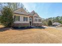 Beautiful home featuring beige siding and a stacked stone facade, enhanced by a lush green lawn at 2037 Castlemaine Circle, Woodstock, GA 30189
