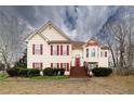 Charming two-story home featuring red shutters, yellow siding, a front porch, and manicured landscaping at 4020 F A A Rd, Cumming, GA 30041