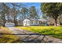 Exterior view featuring a white house, detached garage, long driveway, and mature trees at 2120 Blaylock Dr, Marietta, GA 30062