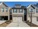 Townhome with a two-car garage, stone accents, neutral colors, and professionally landscaped front yard at 5350 Brooklands Dr, Lithonia, GA 30058