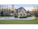 Elegant estate home with stone facade, well-manicured lawn, circular driveway, and arched entryway at 4233 Sandstone Shores Dr, Stonecrest, GA 30038