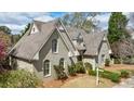 Well-maintained home with a gray brick exterior, arched windows, a dormer, and manicured landscaping at 5 Coventry Close, Avondale Estates, GA 30002
