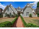 Attractive home featuring a brick facade, arched windows, a dormer, and a brick walkway lined with manicured hedges at 5 Coventry Close, Avondale Estates, GA 30002