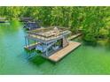 Waterfront property featuring a private boat dock with an upper-level party deck, set on a serene, tree-lined lake at 7640 Harbour Walk, Cumming, GA 30041