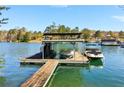 Lake house dock featuring covered boat slips and rooftop deck, perfect for outdoor entertaining and waterfront activities at 7640 Harbour Walk, Cumming, GA 30041