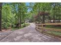 Long driveway leading to the home through a lush, wooded landscape with a charming fence at 7640 Harbour Walk, Cumming, GA 30041