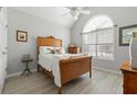 Cozy bedroom featuring vaulted ceiling, arched window, neutral paint, and wood-look flooring at 1152 Strath Clyde Way, Mcdonough, GA 30253