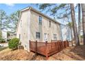 Spacious wooden back deck is attached to a house with light yellow siding and a view of mature trees at 34 Kelso At Peyton Dr, Atlanta, GA 30311