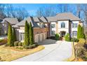 Elegant brick home featuring a three-car garage, manicured lawn, mature evergreens, and a spacious driveway at 4080 Glen Hill Ne Way, Marietta, GA 30066