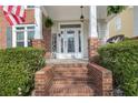 Charming front porch with brick columns, a 'Welcome' sign, and a decorative glass front door at 525 Village Arbor Park, Suwanee, GA 30024