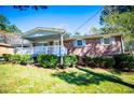 Brick single-story home with shuttered windows, a white porch, and green bushes in the front yard at 5042 Central Church Rd, Douglasville, GA 30135