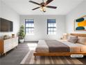 A virtually staged primary bedroom with a ceiling fan, a large bed, and two sunny windows at 6206 Redan Overlook, Lithonia, GA 30058