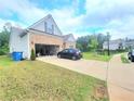 Exterior view showcasing driveway, garage, and landscaping in a well-maintained yard at 1125 Campbell Pine Trl, Lawrenceville, GA 30045
