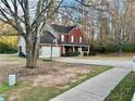 Two-story red brick home with a two-car garage, front porch, and basketball hoop in the driveway at 2703 Regal Cir, Conyers, GA 30012