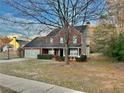 Two-story red brick home with a spacious front yard and mature tree, providing shade and curb appeal at 2703 Regal Cir, Conyers, GA 30012
