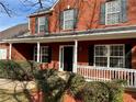 Close up of charming red brick home featuring a cozy front porch with decorative white railings at 2703 Regal Cir, Conyers, GA 30012