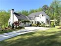 Elegant white home featuring an attached garage covered in climbing vines and a perfectly manicured lawn at 5210 Timber S Trl, Sandy Springs, GA 30342