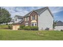 View of the two-story house showing brick and vinyl siding with a large lawn and landscaping at 3370 Flagstone Trce, Ellenwood, GA 30294