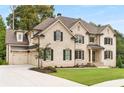Beautiful two-story brick home featuring a three car garage, manicured lawn and dark window shutters at 4827 Basingstoke Dr, Suwanee, GA 30024