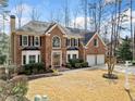 Two-story brick home with a manicured front lawn, two-car garage, trimmed bushes, and an inviting entrance, surrounded by trees at 1904 Rosewood Ln, Woodstock, GA 30189