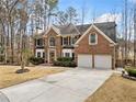 Beautiful two-story brick home featuring a two-car garage, trimmed bushes, and a spacious driveway, surrounded by mature trees at 1904 Rosewood Ln, Woodstock, GA 30189