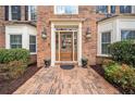 Close-up of a charming brick home entrance featuring a wooden door, elegant lanterns, and professionally landscaped bushes at 1904 Rosewood Ln, Woodstock, GA 30189