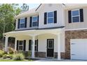 Beautiful home featuring a welcoming front porch, stone accents, and neatly trimmed landscaping at 83 Nyishol Way, Dallas, GA 30157