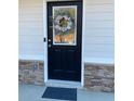 Close-up of a black front door featuring a decorative floral wreath and sidelight window at 83 Nyishol Way, Dallas, GA 30157