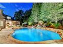 Beautiful pool area with stone waterfall features and lush landscaping at night at 829 Big Horn Holw, Suwanee, GA 30024