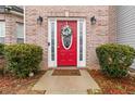 Close up view of a bright red front door adorned with a floral wreath and black sconces at 1644 Cutters Mill Dr, Lithonia, GA 30058