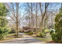 View of the front of the brown home surrounded by mature trees and a long driveway at 360 W Spalding Dr, Atlanta, GA 30328