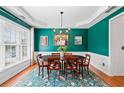 Formal dining room with wainscoting, hardwood floors, a chandelier, and a patterned rug at 3810 Branch Bluff Ln, Cumming, GA 30040