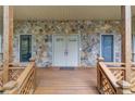 Inviting covered front porch featuring stone accents and a warm wood railing, leading to the front door at 1667 Manhasset Farm Ct, Atlanta, GA 30338