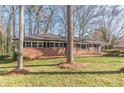 Quaint brick home with dark shutters, complemented by mature trees, nestled in a serene front yard setting at 407 North Ave, Atlanta, GA 30354