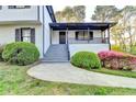 Inviting covered porch with stairs leading to the entrance, complemented by mature landscaping at 4087 Signal Rdg, Lilburn, GA 30047