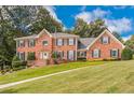 Charming brick home with a well-maintained lawn and symmetrical design, complemented by lush greenery and blue skies at 5581 Stapleton Dr, Dunwoody, GA 30338