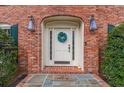 Inviting front door with a festive wreath, set in a brick surround with elegant sconces and a welcoming mat at 5581 Stapleton Dr, Dunwoody, GA 30338