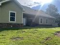 Exterior back of the home with green siding and a well maintained lawn at 10390 Rivertown Rd, Fairburn, GA 30213