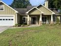 One-story home with an attached garage, a front porch with columns, and green siding at 10390 Rivertown Rd, Fairburn, GA 30213