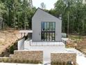 Modern home exterior with black framed windows, stone retaining wall, and lush landscaping at 1171 Lupo Loop, Chattahoochee Hills, GA 30268