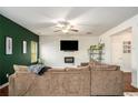 Comfortable living room featuring plush sectional sofa, ceiling fan, and a modern electric fireplace below the mounted TV at 71 Pulaski Ave, Hampton, GA 30228