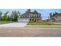 Elegant two-story home showcasing a large driveway, inviting entrance, and charming landscaping at 165 Haverling Pass, Hampton, GA 30228