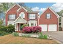 Charming two-story brick home with landscaped yard, blooming flowers and a two-car garage at 2118 Township Dr, Woodstock, GA 30189