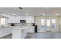 Bright kitchen featuring an island, white cabinetry, stainless steel appliances, and a gray backsplash at 285 Glen Lake Dr, Sandy Springs, GA 30327